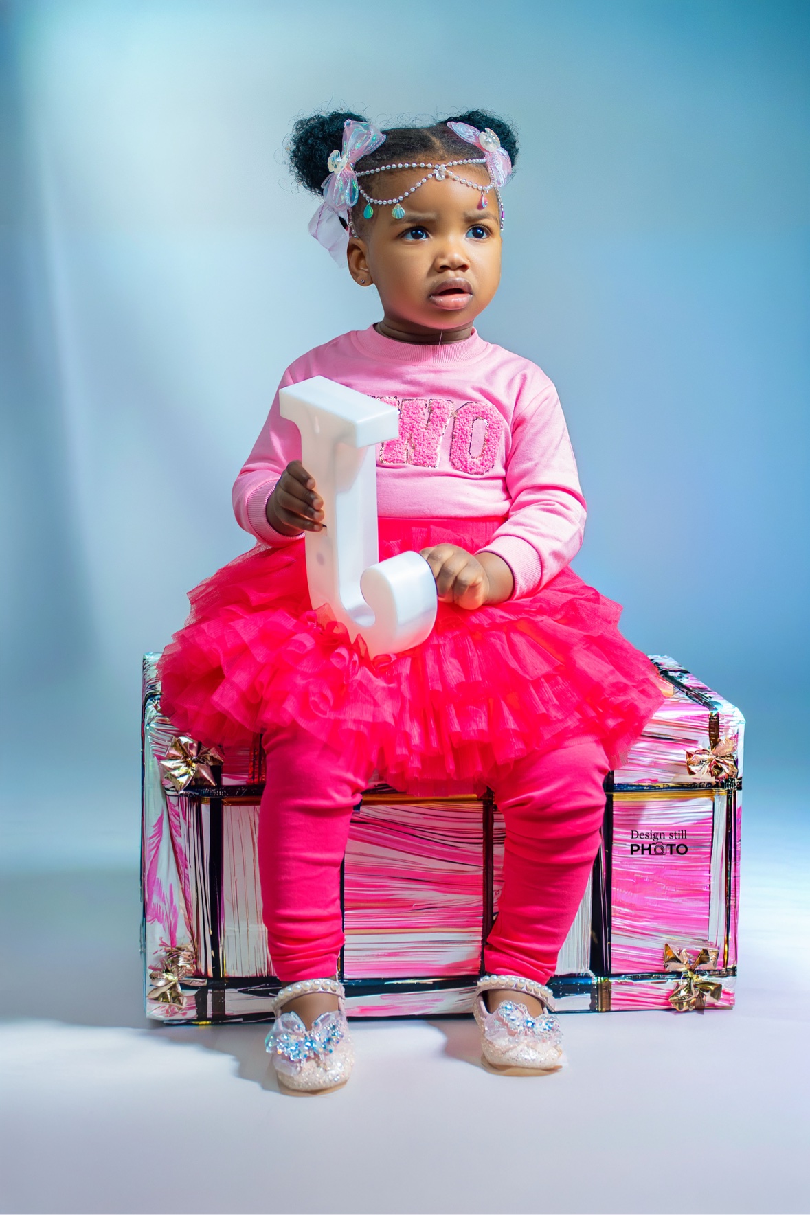 Toddler girl in a pink tutu holding a number 1