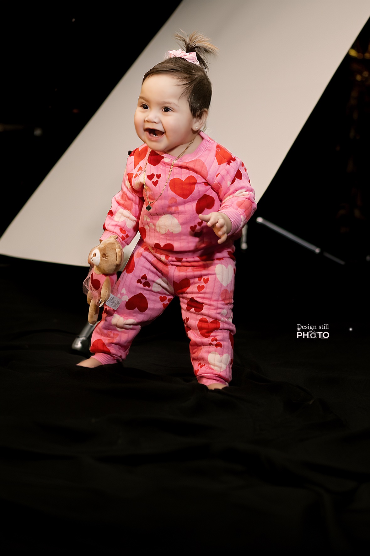 Baby in pink heart pajamas holding a teddy bear