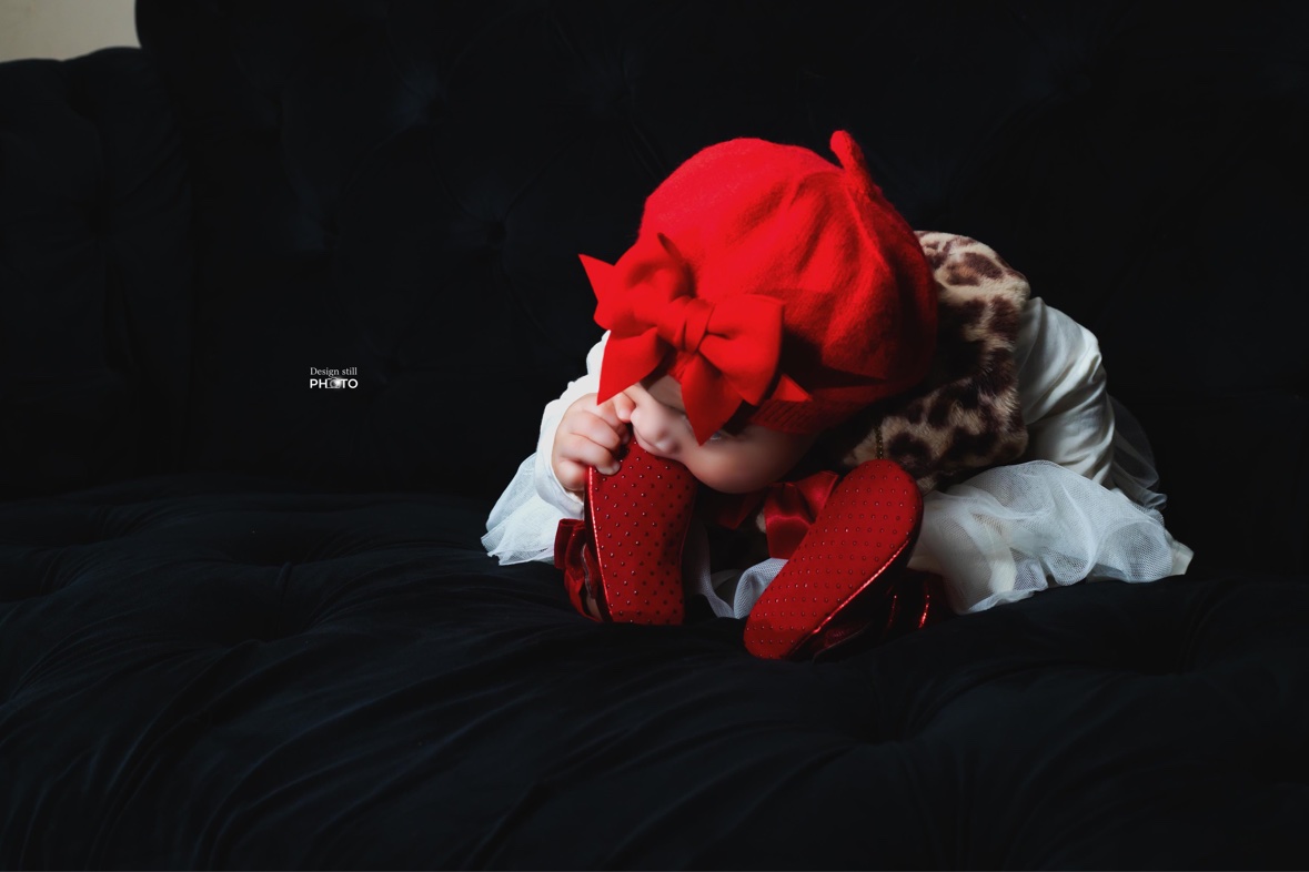Baby in a red beret playing with red shoes
